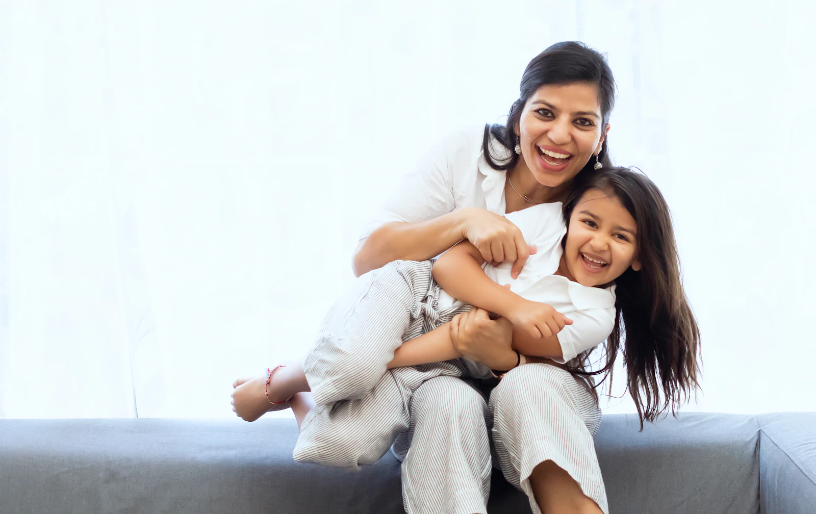 Mother and daughter laughing together on a sofa