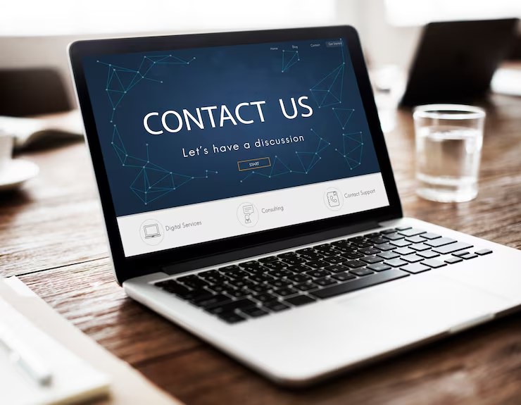 Laptop showing a Contact Us page on a wooden desk