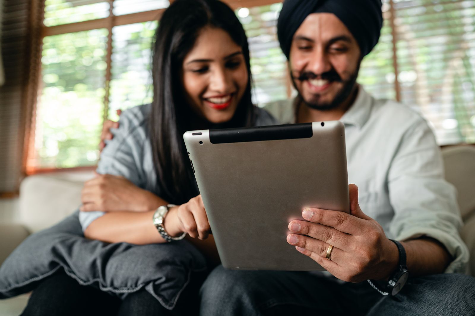 Indian couple smiling while reviewing their investments on a tablet